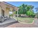 Beautiful backyard featuring a covered patio with hanging plants, a lush lawn, and mature trees at 5283 W Dublin Ct, Chandler, AZ 85226