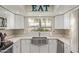 Bright kitchen with white cabinets, stainless steel sink, and quartz countertops with 