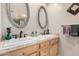 Bright bathroom featuring double sinks, wood cabinetry and custom oval mirrors at 7921 E Bonita Dr, Scottsdale, AZ 85250