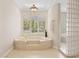 Bathroom featuring a soaking tub, glass block shower, shutters, and neutral tile flooring at 8815 N 65Th St, Paradise Valley, AZ 85253