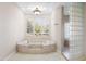 Luxurious bathtub with tile surround, large windows with shutters, and glass block shower nearby at 8815 N 65Th St, Paradise Valley, AZ 85253