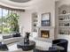 Bright living room featuring a stone fireplace, curved sofa, accent chairs, and a garden view at 8815 N 65Th St, Paradise Valley, AZ 85253