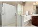 Bright bathroom features a glass-enclosed shower and soaking tub next to a window at 13583 S 177Th Ln, Goodyear, AZ 85338