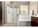 Bright bathroom features a glass-enclosed shower and soaking tub next to a window at 13583 S 177Th Ln, Goodyear, AZ 85338