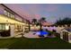 Beautiful backyard with a sparkling pool, lush green lawn, patio, and palm trees at dusk, perfect for entertaining and relaxing at 1429 E Lowell Ave, Gilbert, AZ 85295