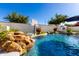 Inviting pool area with rock waterfall, basketball hoop, and manicured landscaping, creating a serene outdoor space at 1429 E Lowell Ave, Gilbert, AZ 85295