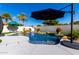 Inviting pool with a waterfall feature, complemented by a large black umbrella, beautiful landscaping and well-maintained deck at 1429 E Lowell Ave, Gilbert, AZ 85295