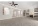 Open-concept living room featuring plush carpet, built-in shelves, and abundant natural light at 15801 W Goldenrod Dr, Surprise, AZ 85374