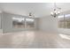 Bright living room with tile floors, large windows offering outdoor views, and an elegant chandelier at 15801 W Goldenrod Dr, Surprise, AZ 85374