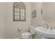 Cozy half-bathroom featuring pedestal sink, neutral tones, and decorative mirror at 16747 W Berkeley Rd, Goodyear, AZ 85395