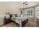 Comfortable bedroom features a ceiling fan, large bed, and windows with plantation shutters at 16747 W Berkeley Rd, Goodyear, AZ 85395