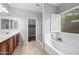 Bright bathroom featuring a large soaking tub, tiled floors, a window with shuttered blinds and a walk-in shower at 16763 W Magnolia St, Goodyear, AZ 85338