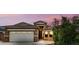 Inviting home exterior with a two-car garage, tidy landscape, and warm lighting at 16763 W Magnolia St, Goodyear, AZ 85338