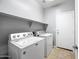 A laundry room featuring a washer, dryer, tile floors, a door, and built-in shelves at 16763 W Magnolia St, Goodyear, AZ 85338
