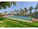 Well-maintained community tennis court surrounded by palm trees and vibrant green grass at 17630 N Somerset Dr, Surprise, AZ 85374