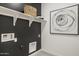 Contemporary laundry room with dark accent wall, white shelving, and modern art at 17731 W Onyx Ave, Waddell, AZ 85355