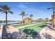 Community bocce ball court with palm trees, covered seating, lake view, and well maintained landscaping at 17900 W Briarwood Dr, Goodyear, AZ 85338