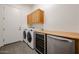 Laundry area with modern appliances, wood cabinets, and stainless steel beverage center at 17900 W Briarwood Dr, Goodyear, AZ 85338