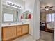 Bathroom with double sinks, wood cabinets, large mirror and view to the bedroom at 18047 W Caribbean Ln, Surprise, AZ 85388