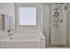 Bright bathroom with tub, shower stall, window, and modern fixtures at 18047 W Caribbean Ln, Surprise, AZ 85388