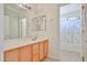 Bright bathroom featuring a large mirror, vanity with storage, and a shower with colorful curtain at 18047 W Caribbean Ln, Surprise, AZ 85388