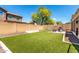 Large backyard featuring artificial turf, mature trees, a grill, and a block wall at 1806 W Fetlock Trl, Phoenix, AZ 85085