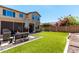 Well-maintained backyard featuring artificial turf, fire pit, grill, and mature landscaping at 1806 W Fetlock Trl, Phoenix, AZ 85085