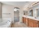 Inviting bathroom with double sinks, a soaking tub, and an open doorway to the bedroom at 21054 N Sansom Dr, Maricopa, AZ 85138