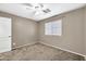 Cozy carpeted bedroom with ceiling fan, window, and neutral paint at 21054 N Sansom Dr, Maricopa, AZ 85138