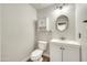 Well-lit powder room featuring a vanity, toilet, and decorative mirror at 21054 N Sansom Dr, Maricopa, AZ 85138