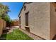 Exterior side view of a home showing textured stucco, a small patch of artificial turf, and desert landscaping at 21059 E Pickett St, Queen Creek, AZ 85142