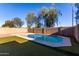 Backyard pool area with privacy wall surrounded by green turf and mature shade trees at 2223 E Crest Ln, Phoenix, AZ 85024