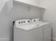 Well-lit laundry room with a Whirlpool washer and dryer plus overhead shelving for extra storage at 22530 N Lynn St, Maricopa, AZ 85138
