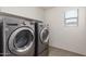 Well-lit laundry room features a stacked washer and dryer for efficient space-saving at 24733 N 96Th Ln, Peoria, AZ 85383