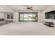 Bright living room features a ceiling fan, neutral carpet, and sliding glass doors that open to the outdoor pool at 24733 N 96Th Ln, Peoria, AZ 85383
