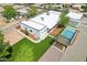 An aerial view of the property featuring a pristine pool, turf lawn, and a modern home design at 3043 E Hartford Ave, Phoenix, AZ 85032