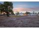 A spacious backyard with a house, trees, and desert landscaping under an evening sky at 3043 E Hartford Ave, Phoenix, AZ 85032