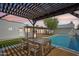 The backyard features a dining table under a pergola next to the sparkling pool, perfect for outdoor entertaining at 3043 E Hartford Ave, Phoenix, AZ 85032