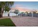 A sunset view of a backyard playground featuring a swing set, climbing bars, and a sandy play area at 3043 E Hartford Ave, Phoenix, AZ 85032