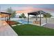 A beautifully landscaped backyard featuring a pool, patio with pergola, and artificial grass for outdoor enjoyment at 3043 E Hartford Ave, Phoenix, AZ 85032