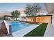 A backyard featuring a sparkling pool, turf grass, and a covered patio area, perfect for relaxation at 3043 E Hartford Ave, Phoenix, AZ 85032