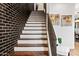 Staircase with dark brick accent wall, modern metal railing, and wood steps at 306 W Culver St, Phoenix, AZ 85003