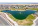 Aerial view of the community with a lake featuring a fountain, pool, playground, and grassy park at 35175 W Marin Ave, Maricopa, AZ 85138