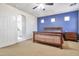 Comfortable main bedroom featuring a wood bed frame, blue accent wall, and ensuite bathroom at 6027 N 132Nd Dr, Litchfield Park, AZ 85340