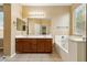 Bathroom featuring dual sinks, vanity, tub, and large mirror at 6103 S 54Th Ave, Laveen, AZ 85339