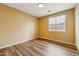 Bright bedroom with wood floors, neutral paint, a window with blinds, and a ceiling light fixture at 6103 S 54Th Ave, Laveen, AZ 85339