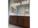 Bathroom featuring vanity with double sinks, mirror, tile floors, and modern lights at 7046 N 84Th Dr, Glendale, AZ 85305