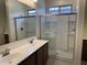 Bright bathroom featuring double sinks, and a glass-enclosed shower with built-in shelving at 7046 N 84Th Dr, Glendale, AZ 85305