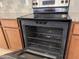 A black electric oven with an open door is surrounded by brown cabinets and granite countertops at 7046 N 84Th Dr, Glendale, AZ 85305