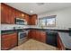 Well-maintained kitchen with dark wood cabinets, stainless steel appliances, and black granite countertops at 7309 W Getty Dr, Phoenix, AZ 85043